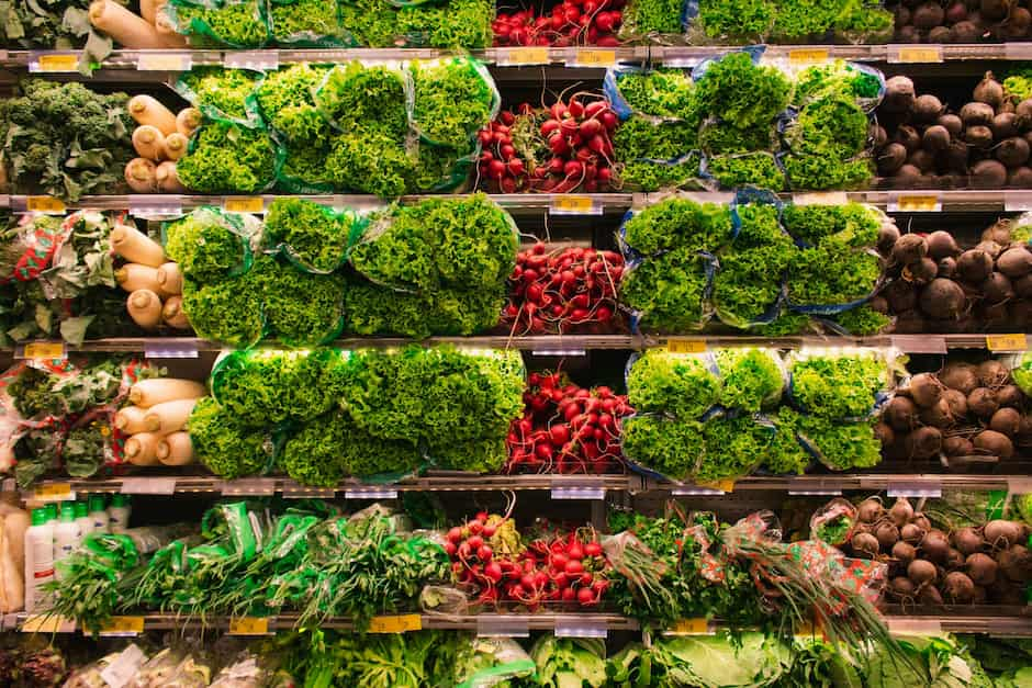 grocery aisle produce shelf stocked with lettuce and greens