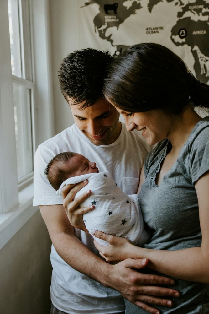 balancing Parenting and the PE Exam new parents embracing their newborn baby and smiling